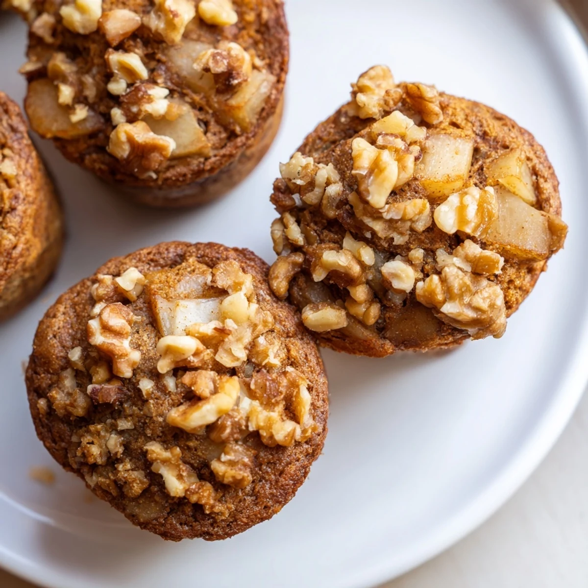 Golden-brown Seasonal Spiced Pear and Walnut Muffins, freshly baked with a delightful walnut crumble topping.