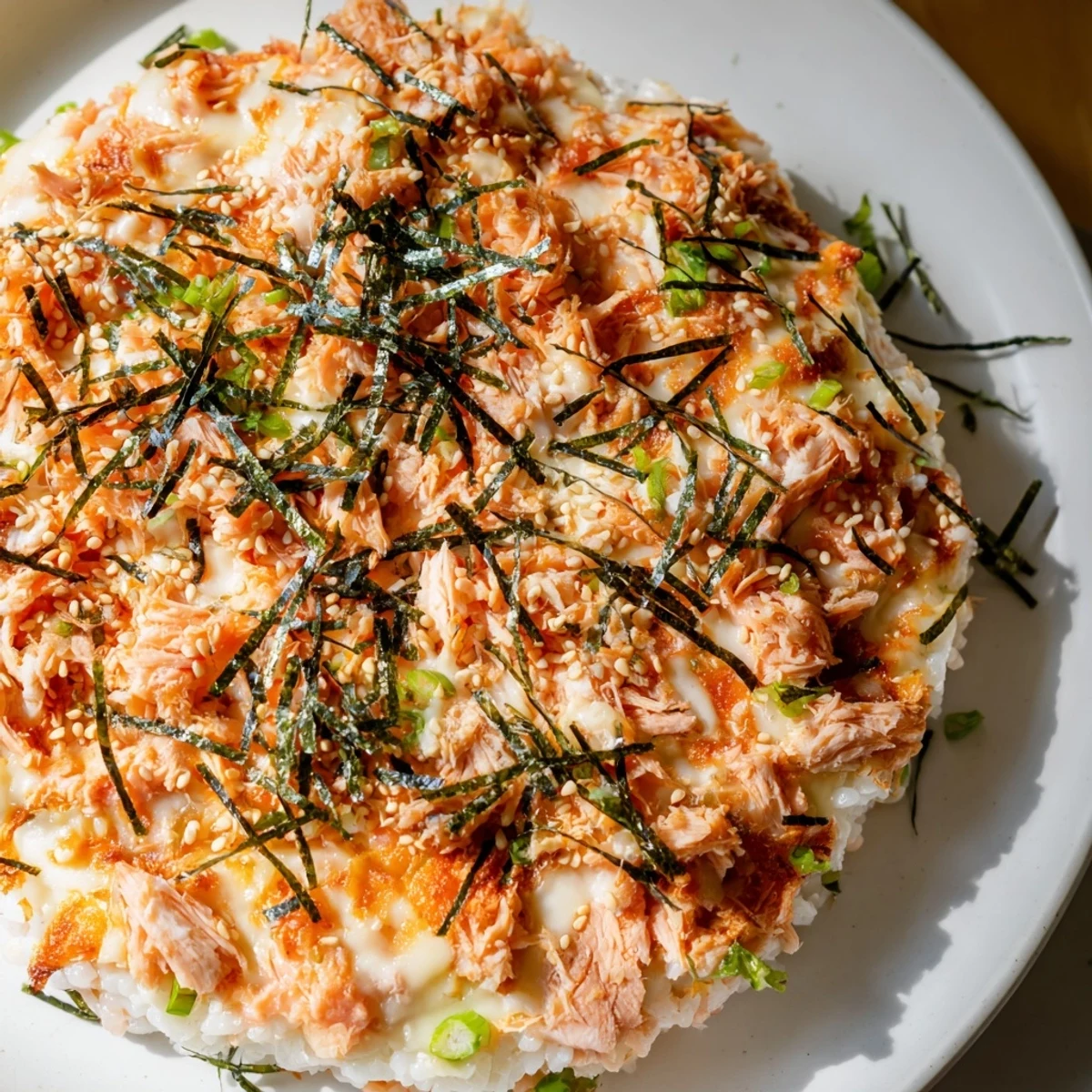 Delectable creamy salmon sushi bake with a bubbly, golden cheese crust and fragrant sesame seeds on top.