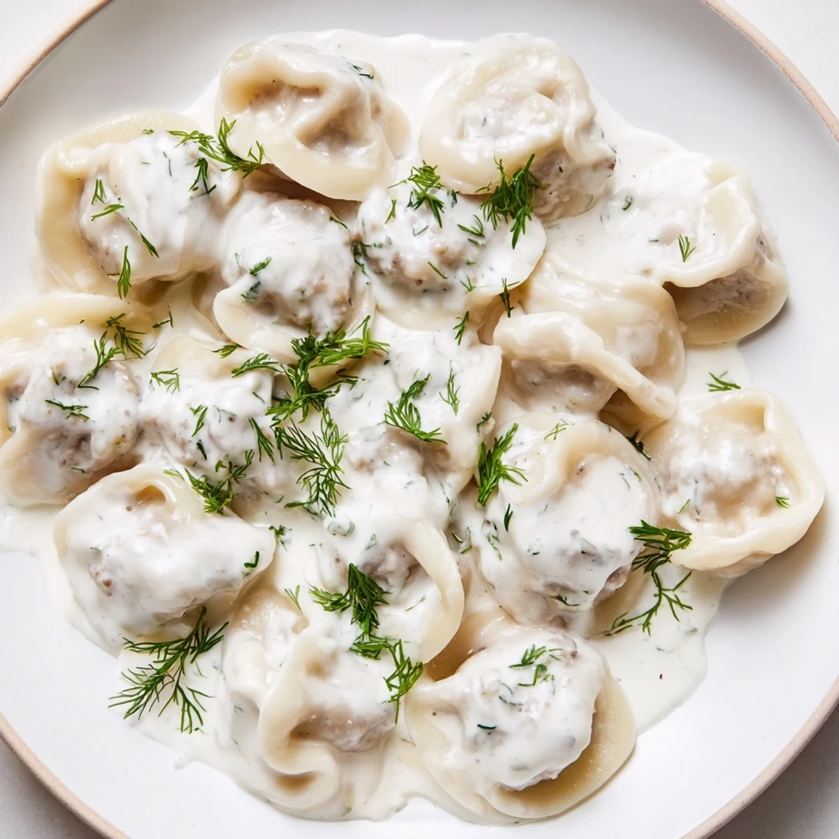 Steaming hot Russian pelmeni, tender meat-filled dumplings, swimming in a rich sour cream sauce.