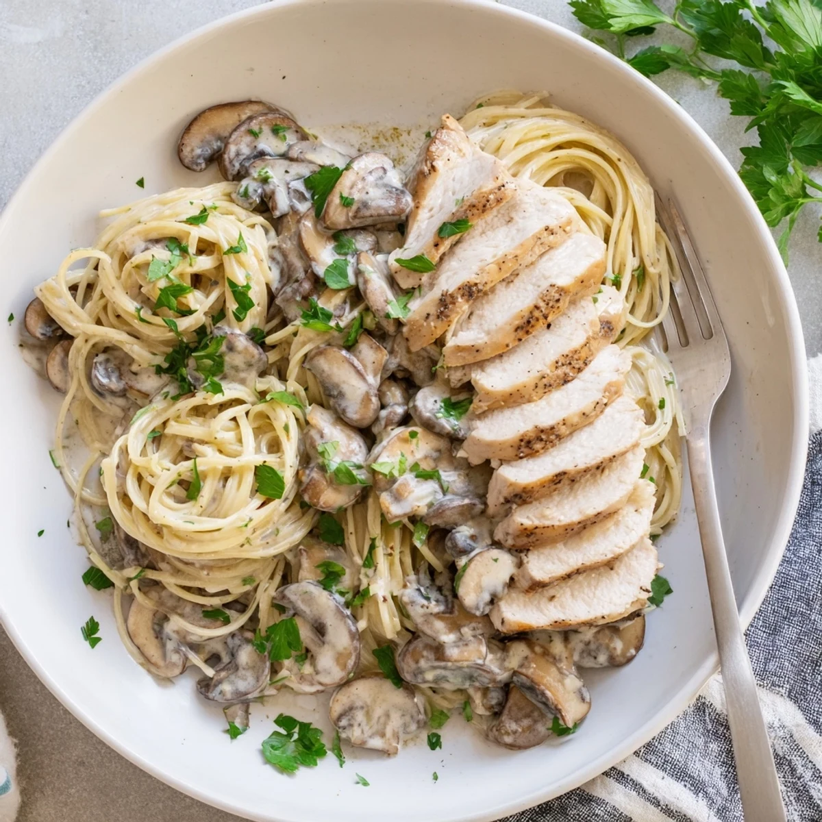 Golden sautéed mushrooms and onions mingle in a light cream sauce with whole wheat spaghettini and juicy chicken strips, served steaming in a white bowl.  