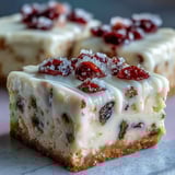 Golden-baked Cranberry Bliss Bars topped with zesty cream cheese frosting and sugared cranberries.