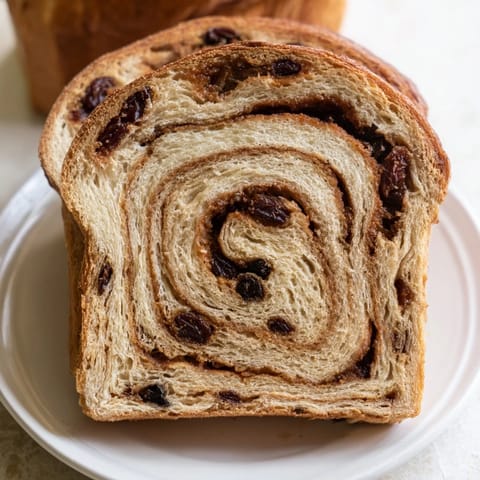 A close-up of a delightful loaf of Homemade Cinnamon Swirl Raisin Bread, showing the swirl.