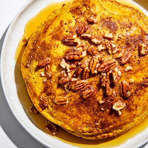 Golden-brown pumpkin spice pancakes cooking on a griddle, filling the kitchen with warm cinnamon and ginger aromas.