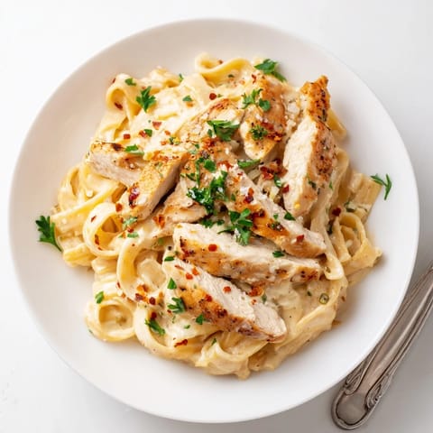 Tender slices of Cajun Chicken Alfredo tossed with silky Alfredo sauce, ready to be served with a glass of white wine.