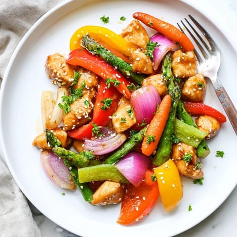 Golden-brown Sheet Pan Honey Garlic Chicken nestled beside vibrant roasted bell peppers and asparagus, glistening with a sweet-savory glaze.  