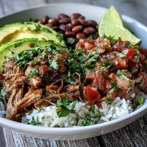 A close-up of a hearty Mexican carnitas bowl featuring tender shredded pork, vibrant salsa, and cilantro garnish.  