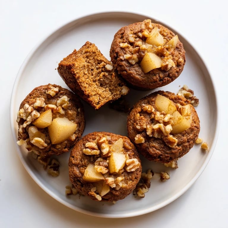 Close-up of fluffy Seasonal Spiced Pear and Walnut Muffins revealing juicy pear pieces and warming spices.
