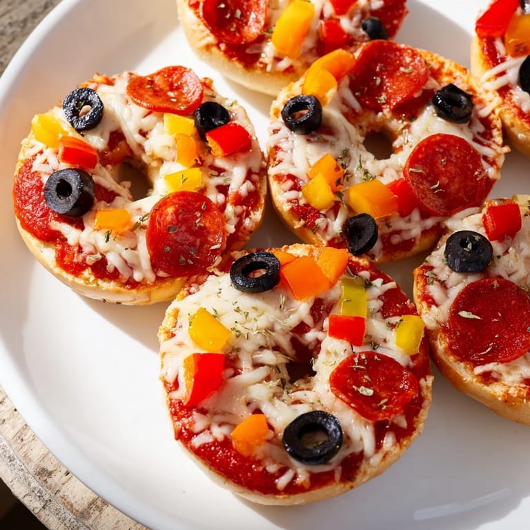 Cheese melting atop mini bagel pizzas, ready to eat after air frying, with pepperoni and olives.