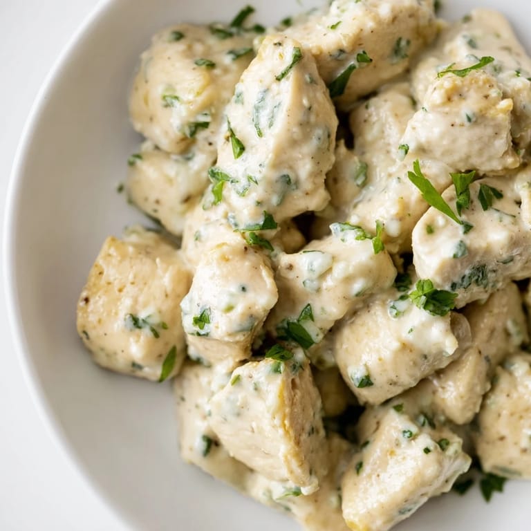 Spicy jalapeño ranch chicken salad garnished with fresh cilantro and chives, served on a rustic wooden table for a hearty meal.